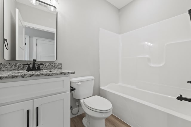 full bathroom with washtub / shower combination, vanity, wood finished floors, and toilet