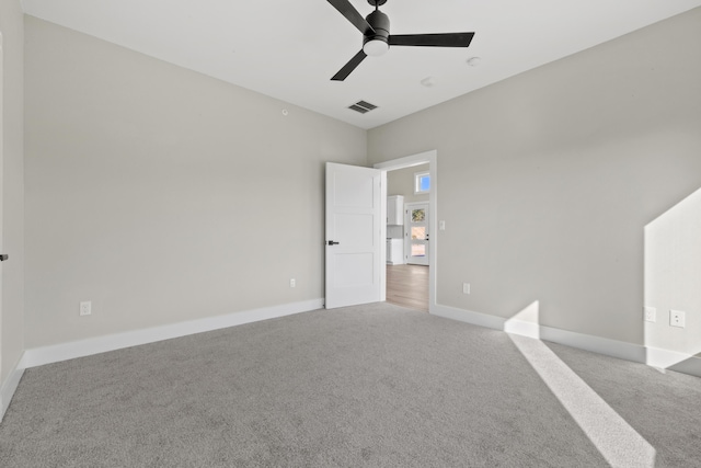 carpeted spare room with baseboards, visible vents, and ceiling fan