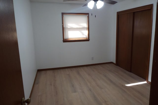 unfurnished bedroom with light wood-type flooring, a ceiling fan, baseboards, and a closet