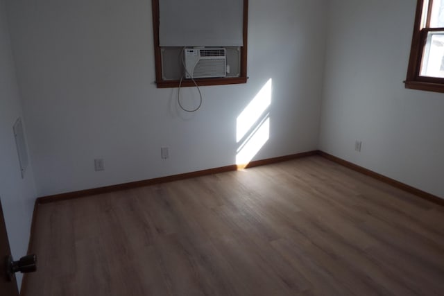 spare room featuring cooling unit, wood finished floors, and baseboards