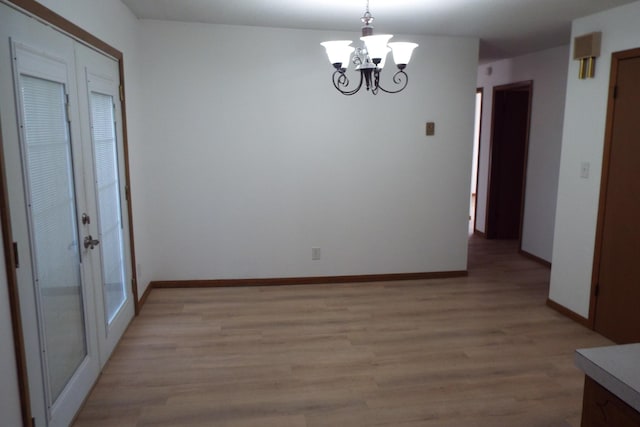 unfurnished dining area with an inviting chandelier, light wood-style flooring, and baseboards