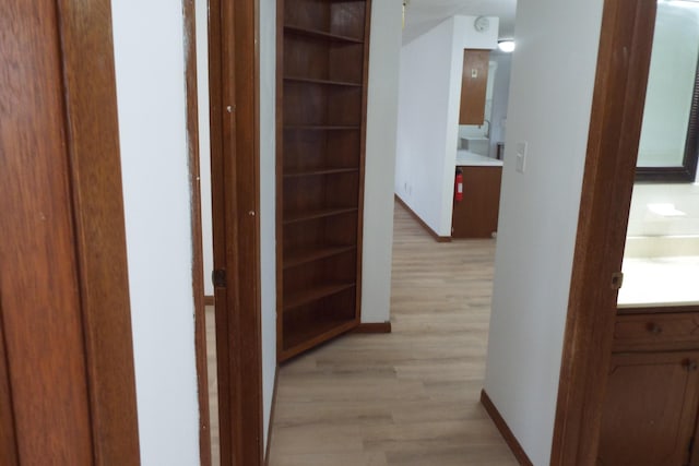 corridor with light wood-style floors and baseboards