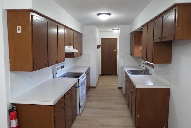 kitchen with under cabinet range hood, electric range, decorative backsplash, and a sink