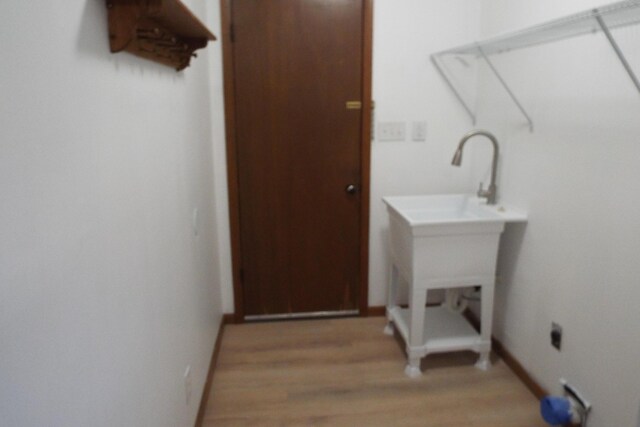 laundry area featuring laundry area, baseboards, and light wood finished floors