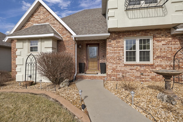 property entrance with roof with shingles and brick siding