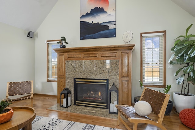 sitting room with high vaulted ceiling, a fireplace, and wood finished floors