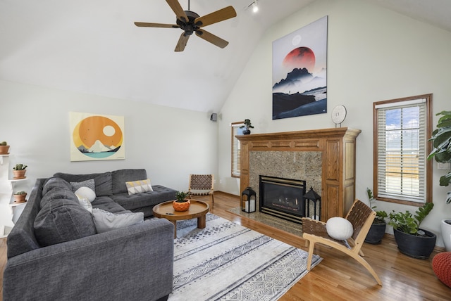 living area featuring a ceiling fan, a premium fireplace, high vaulted ceiling, and wood finished floors