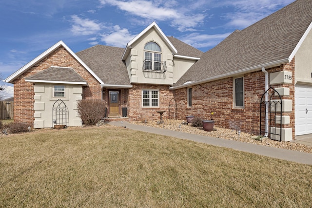 traditional-style home with a garage, brick siding, a shingled roof, stucco siding, and a front yard