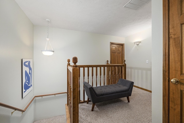 hall with baseboards, a textured ceiling, visible vents, and carpet flooring