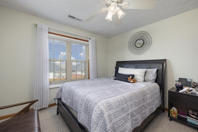 bedroom featuring a textured ceiling, ceiling fan, visible vents, baseboards, and carpet