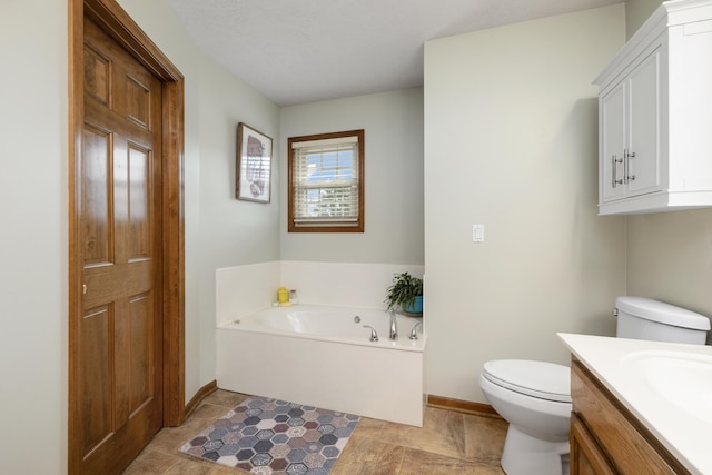 bathroom with toilet, a garden tub, baseboards, and vanity