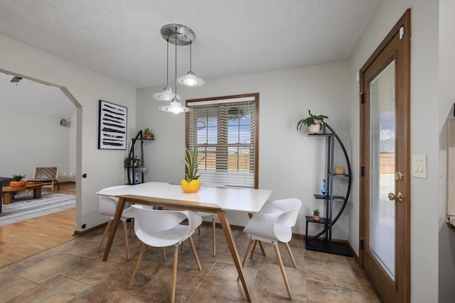 dining space featuring baseboards and arched walkways