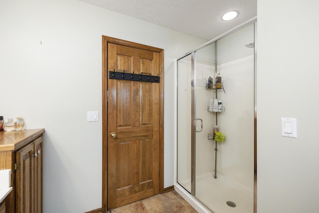 full bathroom featuring a shower stall and a textured ceiling