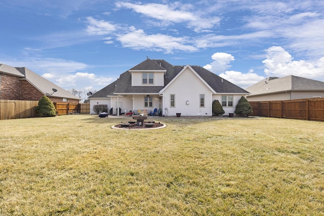 rear view of house featuring a fenced backyard, a lawn, and a patio