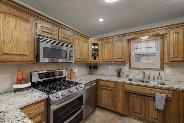 kitchen with appliances with stainless steel finishes, brown cabinets, and a sink