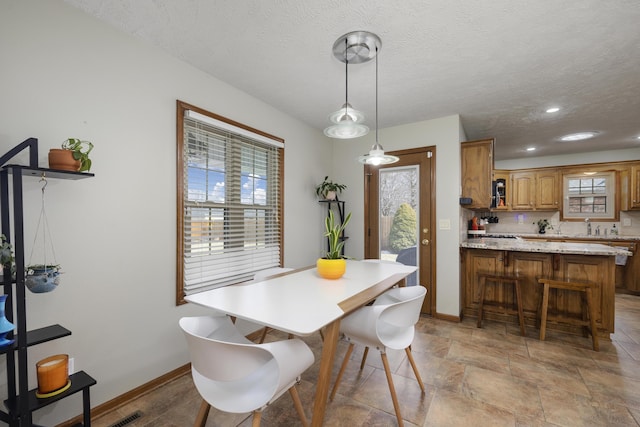 dining area with a textured ceiling, stone finish floor, recessed lighting, and baseboards