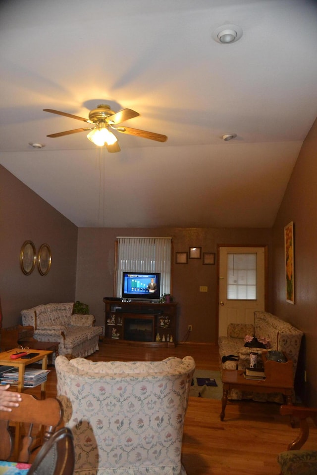 living room with a ceiling fan, lofted ceiling, and wood finished floors