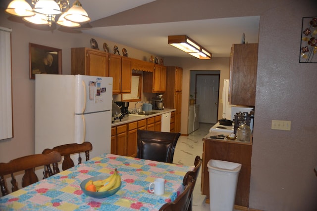 kitchen with white appliances, light countertops, a sink, and brown cabinetry