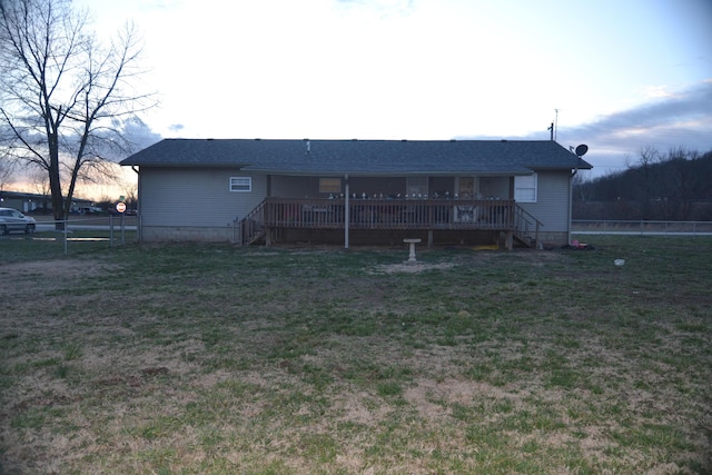 rear view of property featuring fence and a lawn