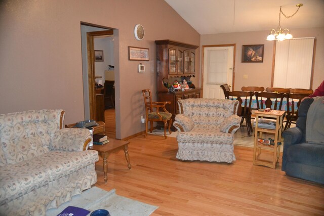 living area with lofted ceiling, a chandelier, light wood-style flooring, and baseboards