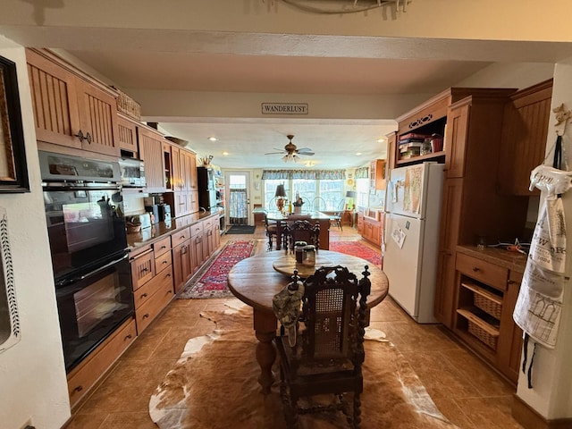 kitchen with recessed lighting, stainless steel microwave, dobule oven black, freestanding refrigerator, and brown cabinetry