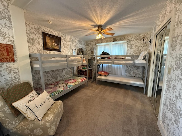 carpeted bedroom featuring wallpapered walls, a ceiling fan, and a textured ceiling