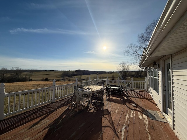 wooden deck with outdoor dining area and a rural view