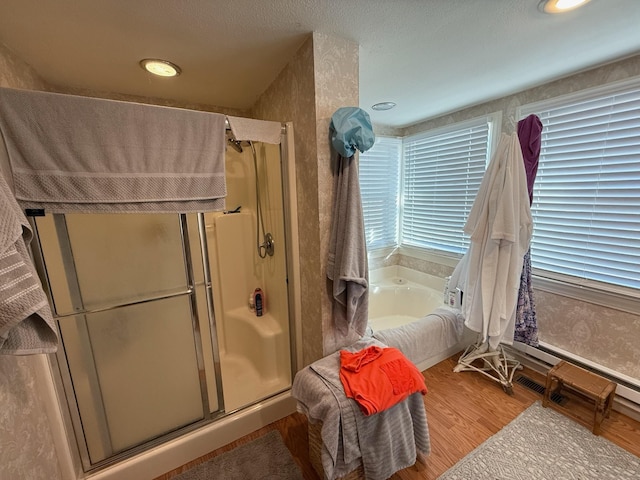 full bathroom with a textured ceiling, wood finished floors, a shower stall, and a bath