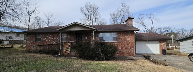 view of front of house featuring a garage, brick siding, driveway, a chimney, and a front yard