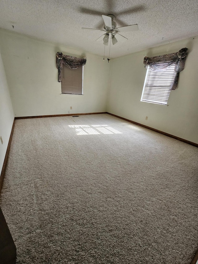 spare room with carpet, baseboards, ceiling fan, and a textured ceiling