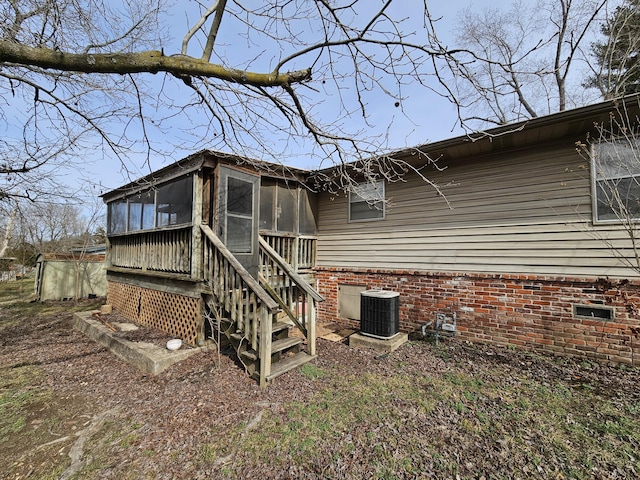 back of property with central AC unit and a sunroom