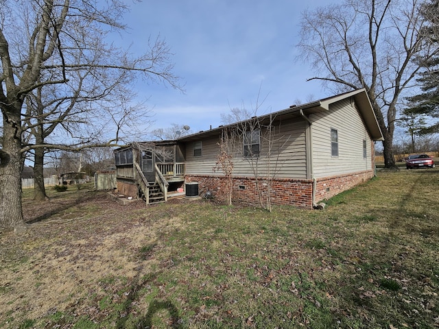 rear view of house featuring a sunroom, central AC unit, and a yard