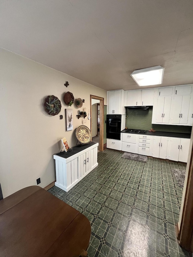 kitchen featuring dark countertops, white cabinetry, black appliances, and dark floors