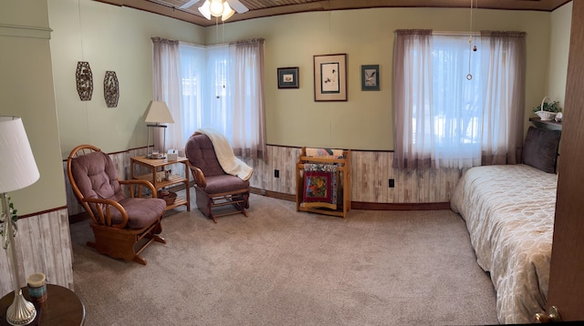 bedroom with carpet floors, wainscoting, and wood walls