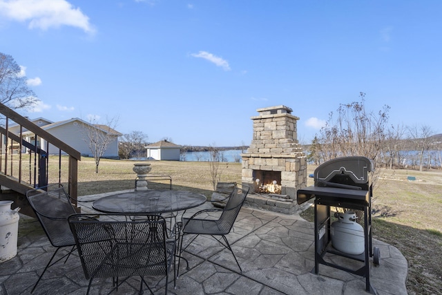 view of patio with outdoor dining space, an outdoor stone fireplace, and a grill