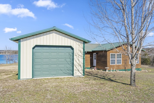 view of front of home featuring metal roof, driveway, a front lawn, and an outdoor structure