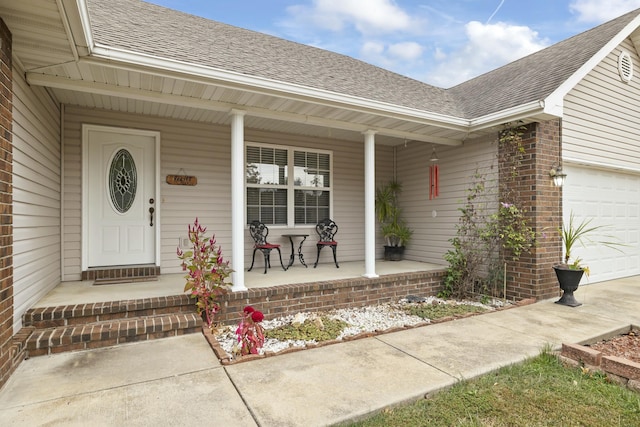 entrance to property with roof with shingles, a porch, and brick siding