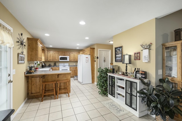 kitchen with light tile patterned floors, recessed lighting, a peninsula, white appliances, and a sink