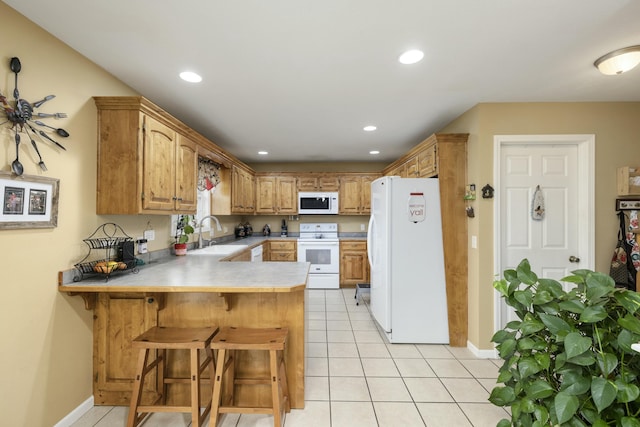 kitchen with light tile patterned floors, light countertops, a sink, white appliances, and a peninsula