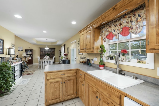 kitchen with light tile patterned floors, a peninsula, a sink, and light countertops