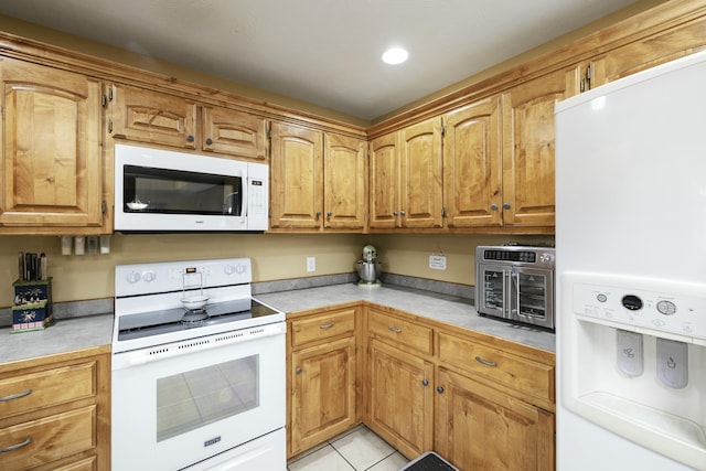 kitchen featuring light countertops, white appliances, light tile patterned flooring, and brown cabinets