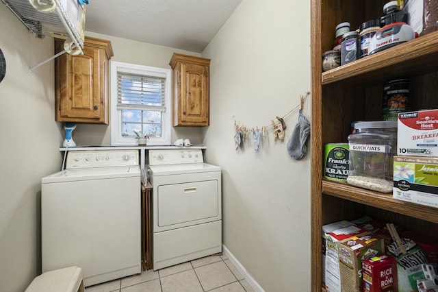 laundry area with light tile patterned floors, washer and clothes dryer, cabinet space, and baseboards