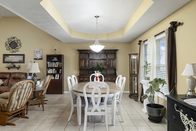 dining space featuring baseboards, a raised ceiling, and light tile patterned flooring