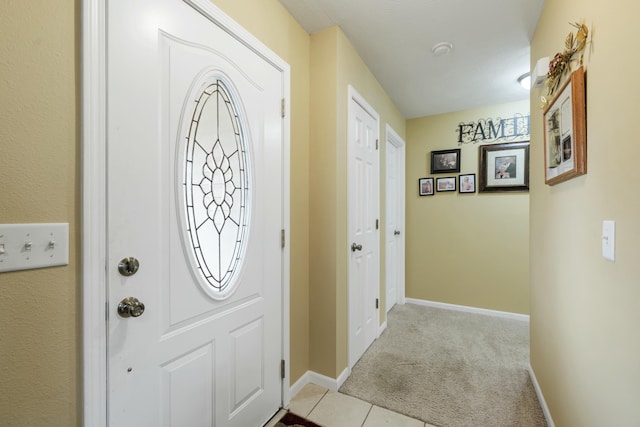 foyer with light colored carpet, baseboards, and light tile patterned floors