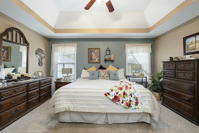 bedroom featuring a ceiling fan, a tray ceiling, and carpet flooring