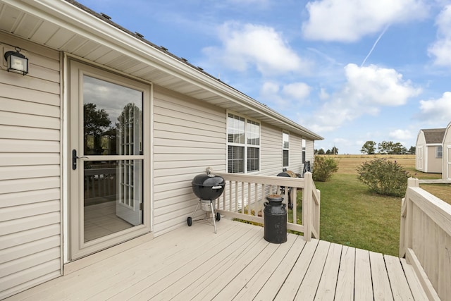 deck featuring a storage shed, a grill, a lawn, and an outbuilding