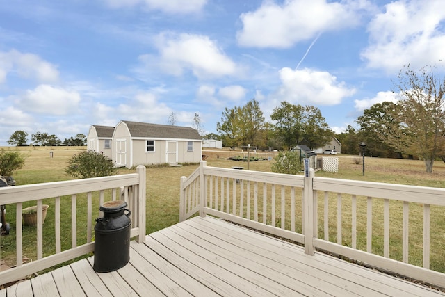 wooden terrace with a storage shed, a yard, and an outbuilding