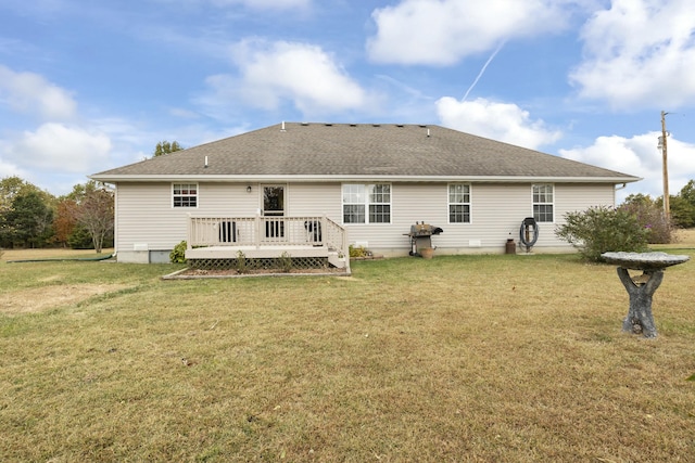 rear view of house with a deck, a yard, and roof with shingles