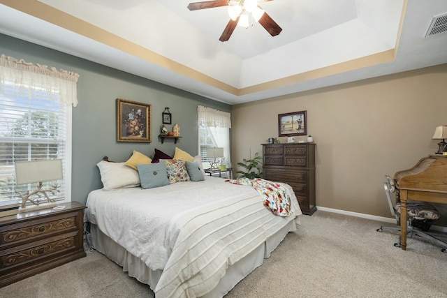 bedroom with light carpet, baseboards, visible vents, and a tray ceiling