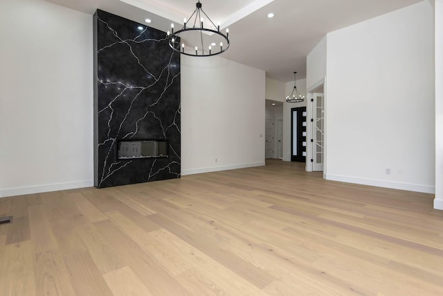 unfurnished dining area with baseboards, wood finished floors, and a notable chandelier